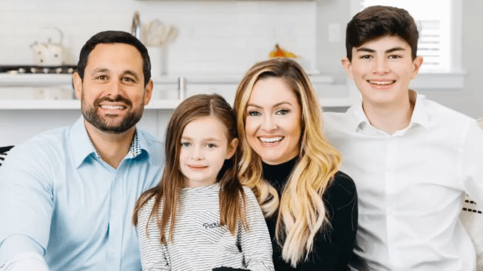 Smiling family of four sitting together in a cozy, well-lit room.