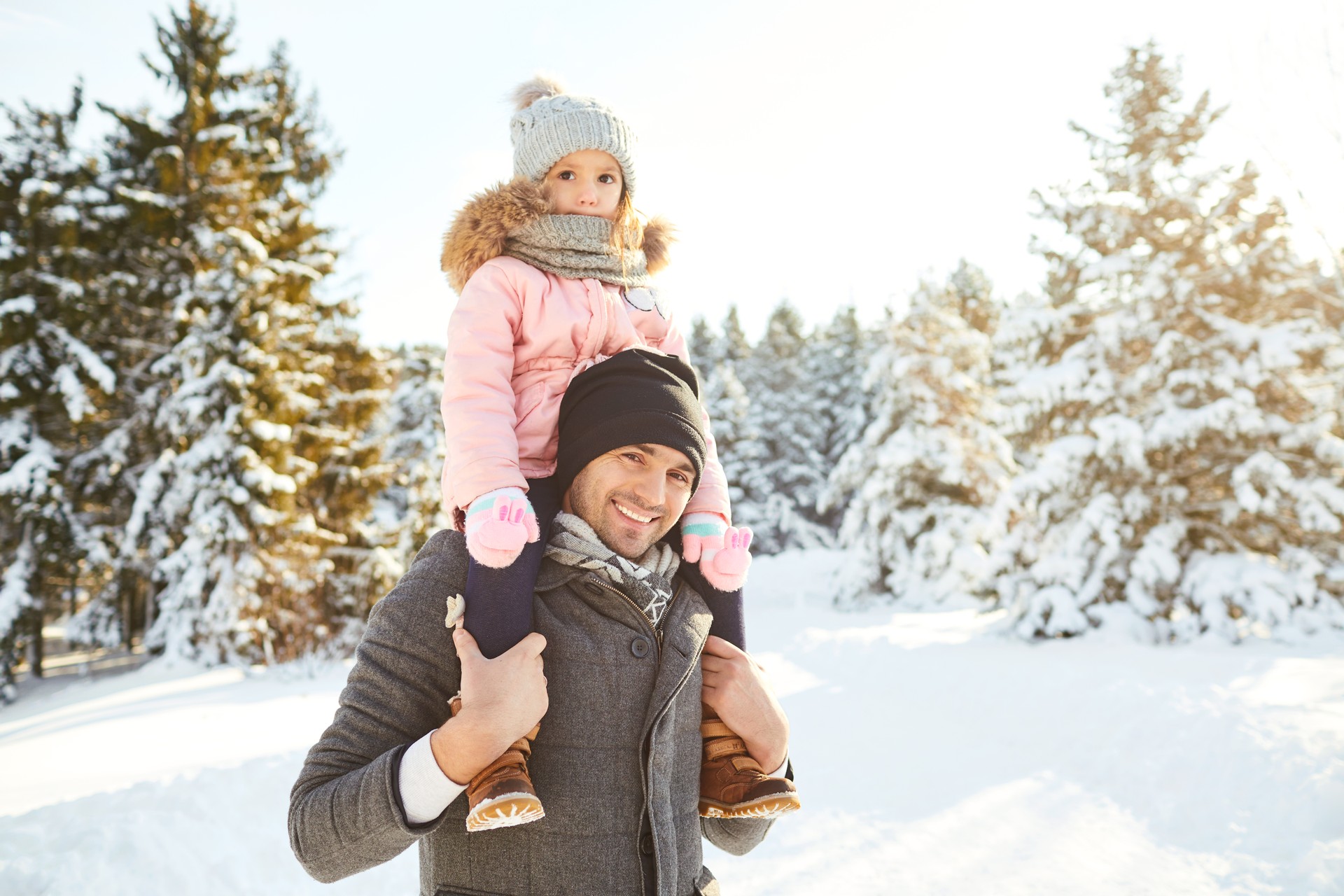 Father with his daughter on his shoulders in the winter in the park