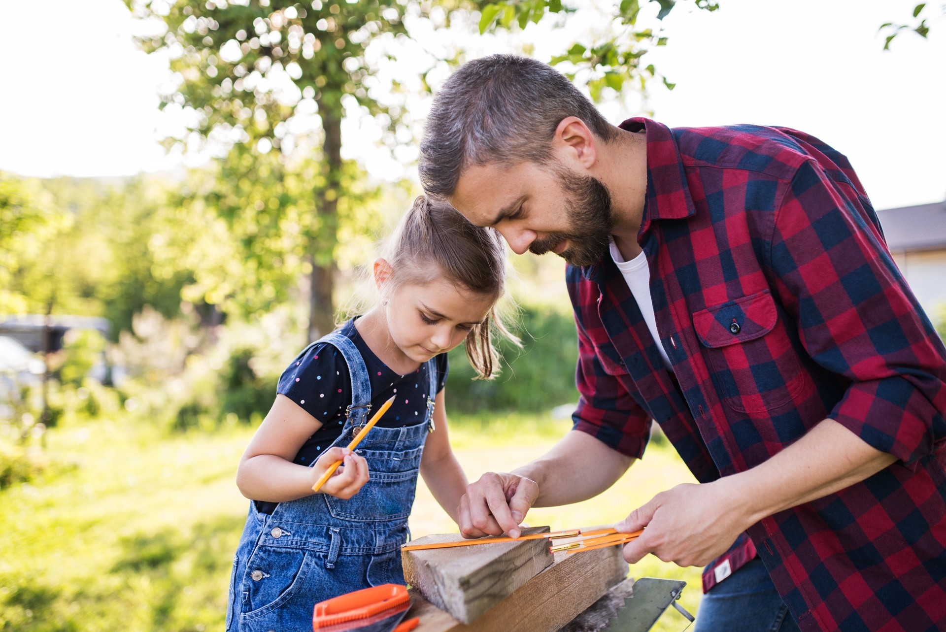 Father with a small daughter outside, making wooden birdhouse.