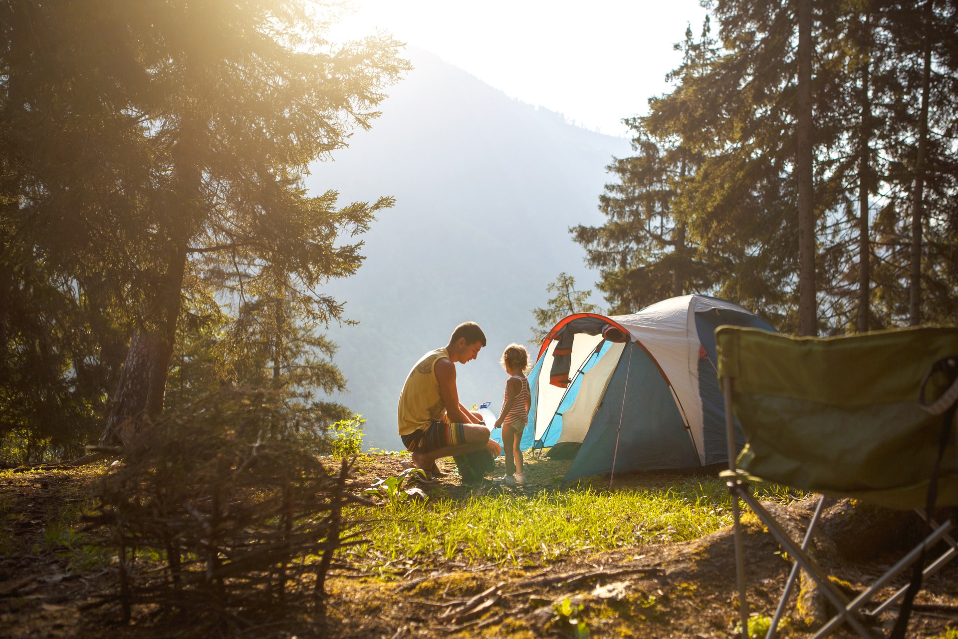 Dad and daughter of 2 years old near a tent in a camping in the forest in the mountains.Family outdoor recreation, eco-friendly adventures, survival in the wild.