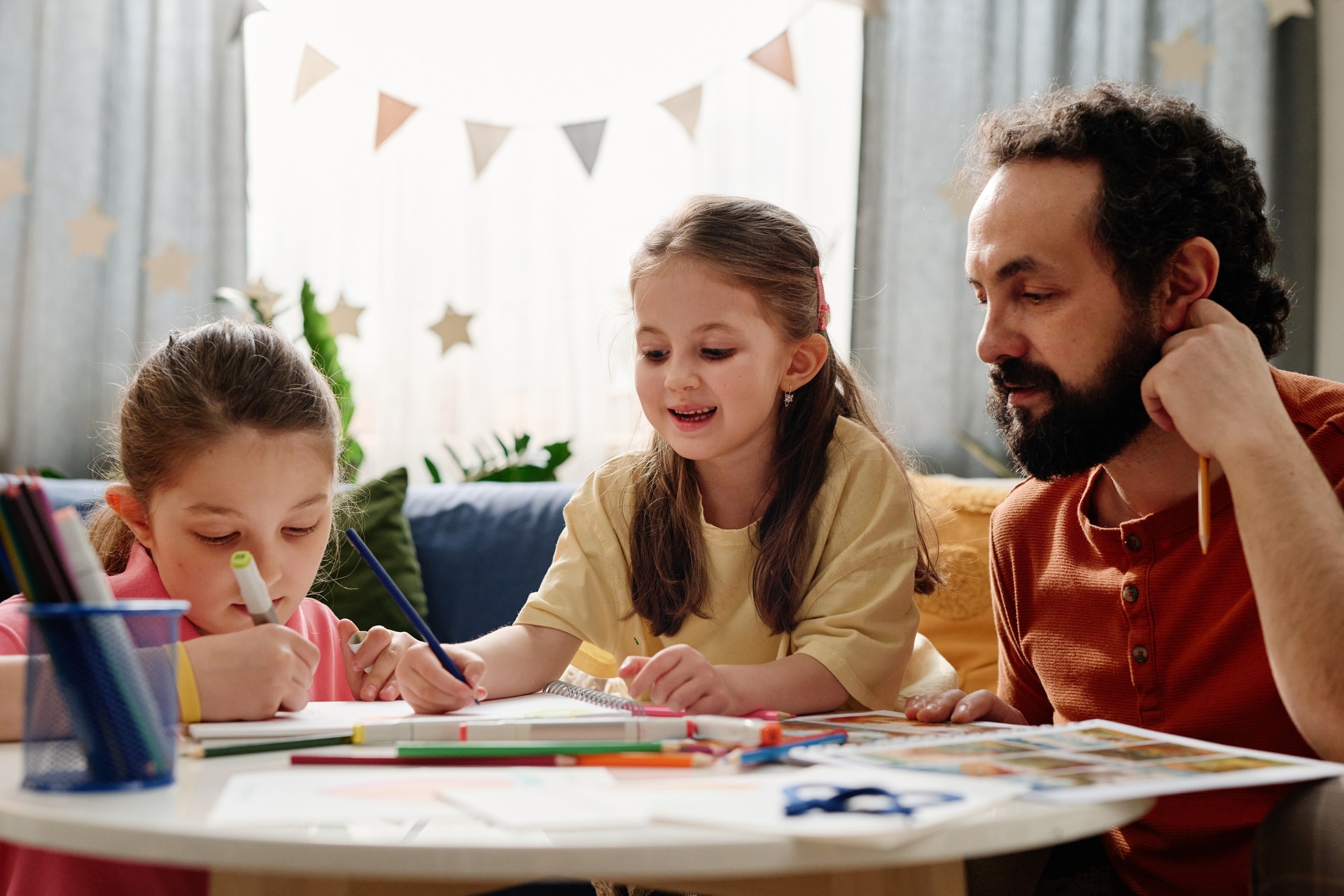 Father Guiding Daughters in Coloring Project at Home